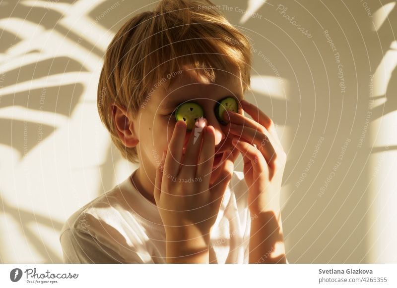 Spiel von Licht und Schatten Porträt jungen kaukasischen niedlichen Jungen mit blonden Haaren im Inneren des Hauses. Spaß Zeit Gurken Augen schön Gesicht