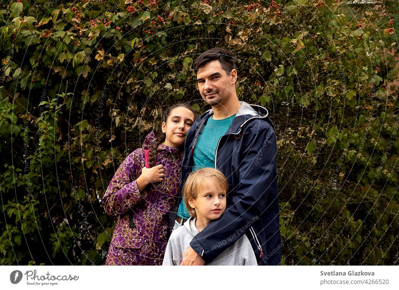 Glückliche Familie Vater auf einen Spaziergang im Park mit seinem Sohn und Tochter. Elternteil umarmt Kinder. Mann männlich Junge Mädchen Teenager Jugendliche