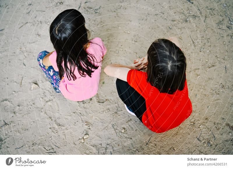 Zwei Mädchen hocken auf dem Sandboden Kinder Geschwister Schwestern Familie Hocke zusammen Strand Ausflug Familienausflug Familienleben Kindheit Freude Glück