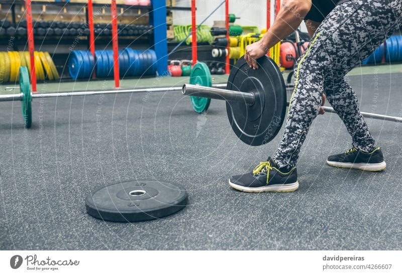 Mann hockt und verändert die Scheiben der Gewichtheberstange Gewichtheben unkenntlich sich[Akk] ändernd vorbereitend Bar Curl-Hantel Kurzhantel Bodybuilder