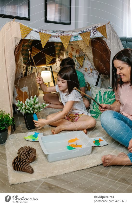 Glückliche Mutter und Tochter Camping zu Hause spielen diy Angeln Spiel Heimaturlaub diy Angelspiel Familie Spaß zu Hause Lächeln Diy-Zelt Angelrute Lager