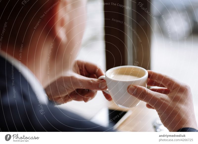 Ein Mann in einem Business-Anzug hält eine Tasse heißen Kaffee in seinen Händen. Morgen Geschäftsmann im Café.Kopieren Raum. trinken Pause männlich Frühstück