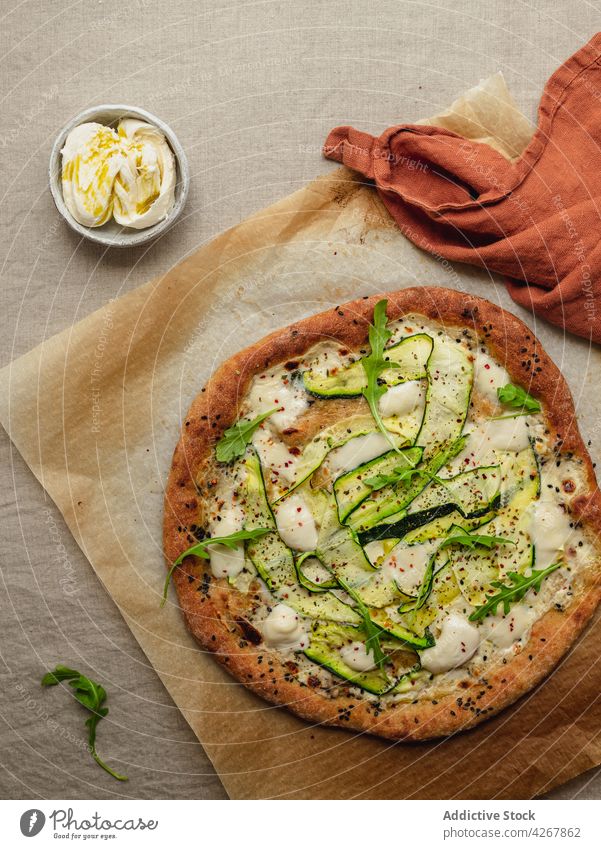 Leckere Pizza mit Zucchinischeiben auf geschmolzenem Mozzarellakäse Squash Rucola Mittagessen Abendessen Mahlzeit Lebensmittel geschmackvoll Pergament Papier