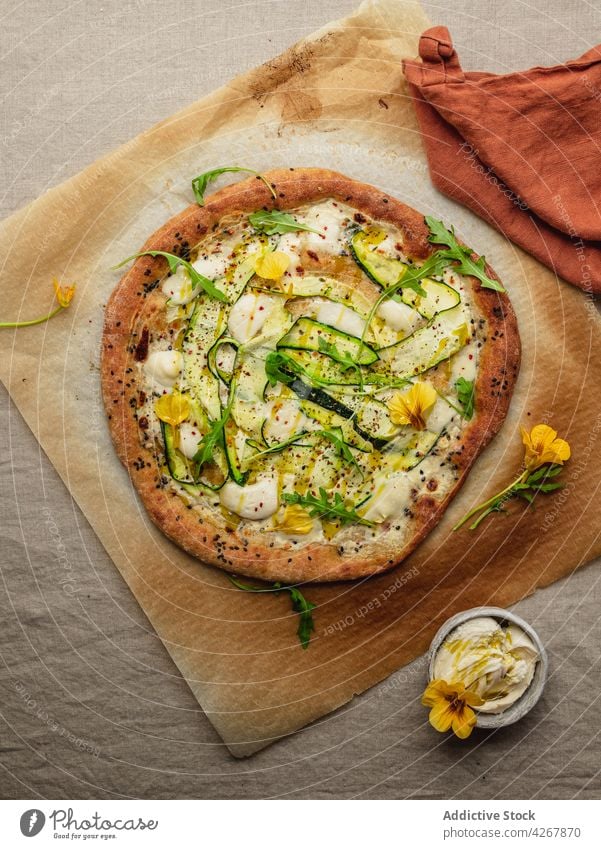 Leckere Pizza mit Zucchinischeiben auf geschmolzenem Mozzarellakäse Squash Rucola Mittagessen Abendessen Mahlzeit Lebensmittel geschmackvoll Pergament Papier