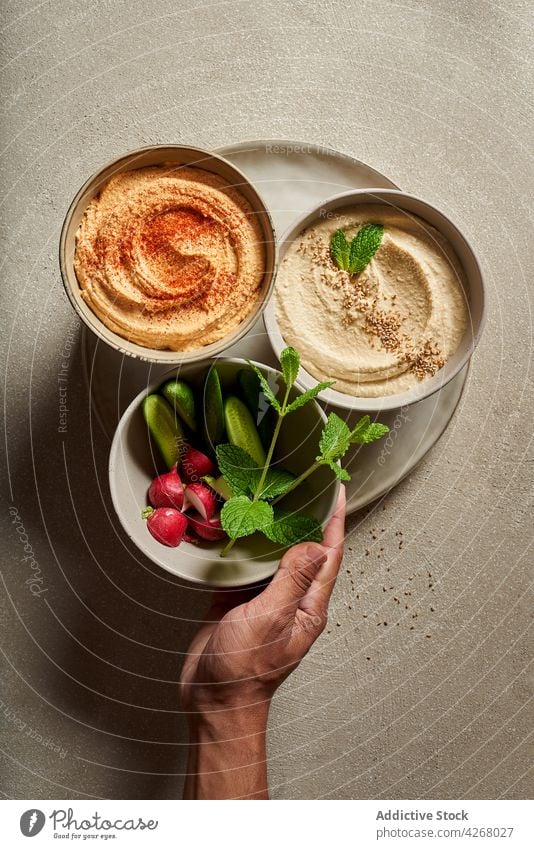 Schale mit buntem Hummus, serviert auf dem Tisch mit frischem Gemüse Person Salatgurke Rettich Mahlzeit Lebensmittel sortiert Schalen & Schüsseln Ernährung