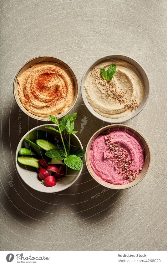 Schale mit buntem Hummus, serviert auf dem Tisch mit frischem Gemüse Salatgurke Rettich Mahlzeit Lebensmittel sortiert Schalen & Schüsseln Ernährung organisch