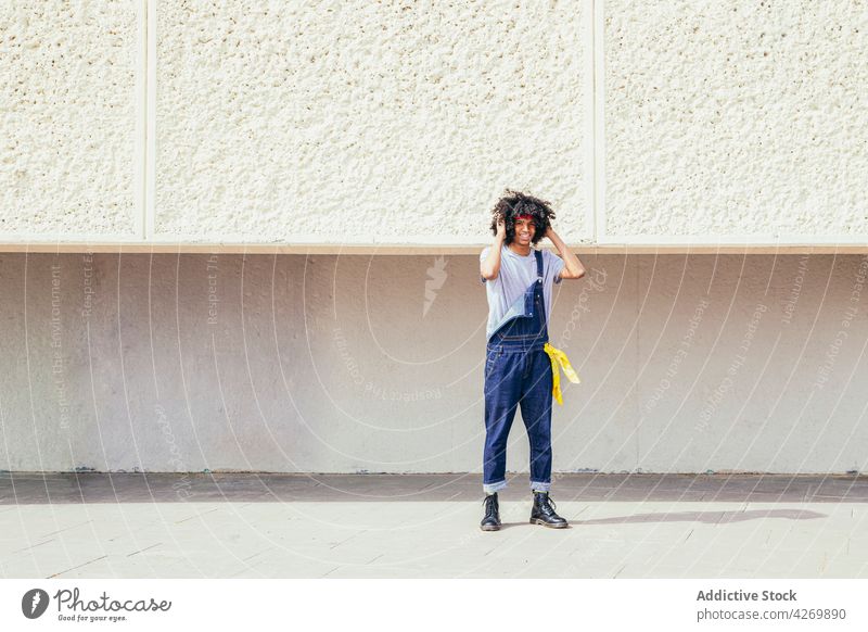 Zufriedener schwarzer Mann in alter Kleidung auf dem Gehweg Haare berühren Inhalt Stil altehrwürdig freundlich genießen Afro-Look Frisur Straßenbelag heiter