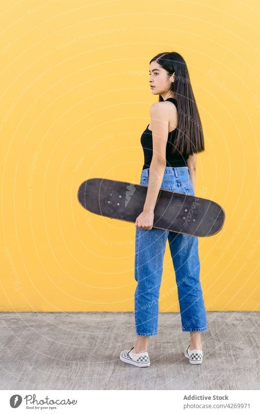 Skateboarder in Freizeitkleidung auf dem Bürgersteig auf gelbem Hintergrund Skater cool Zeitgenosse Generation freie Zeit Lifestyle Teenager Straßenbelag Gerät