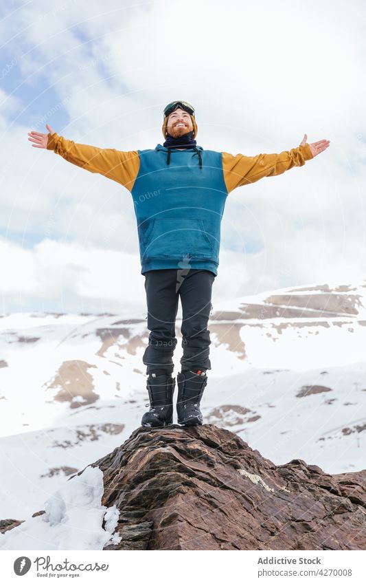 Lächelnder Sportler mit ausgestreckten Armen auf einem Bergrücken im Winter ausdehnen Berge u. Gebirge Freiheit Inhalt Leben offen Natur Hochland Winterzeit