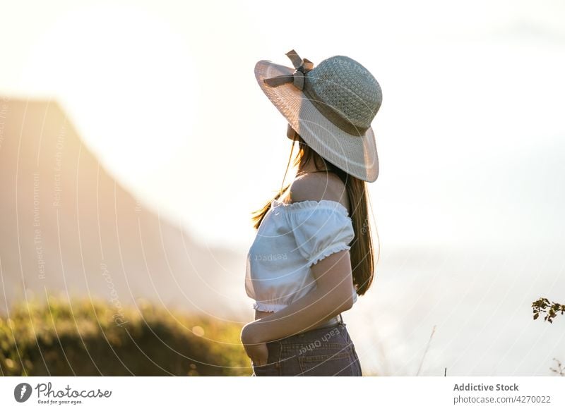 Frau mit Hutkrempe und stehend auf grüner Wiese Rasen verträumt Landschaft friedlich Sommer Stil sensibel Natur Gelassenheit grasbewachsen trendy Vorschein