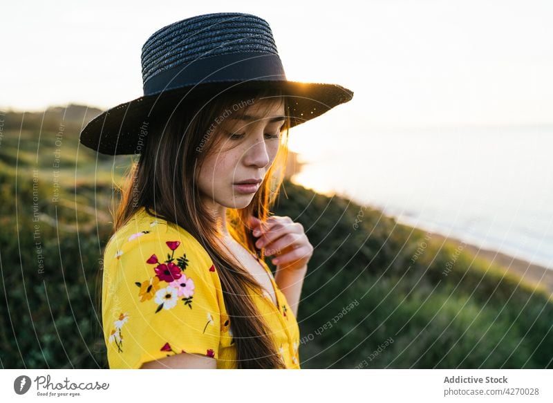 Junge Frau steht auf einem Rasenstück Sonnenkleid Landschaft Natur verträumt Grasland Wiese grasbewachsen jung Feld Hut Vorschein Gelassenheit Anmut feminin