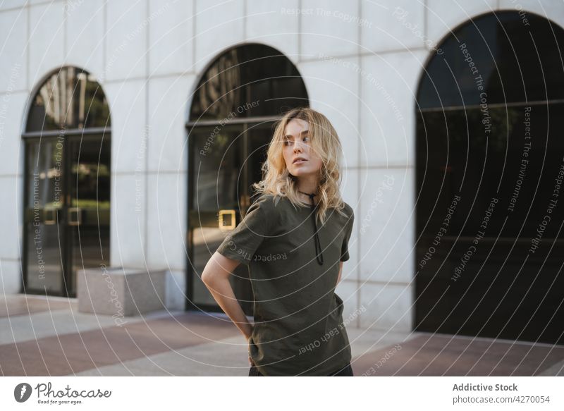 Coole Frau mit Hut, die sich auf dem Bürgersteig der Stadt ausruht cool Individualität Streetstyle Beine gekreuzt Zeitgenosse Generation Laufsteg Porträt