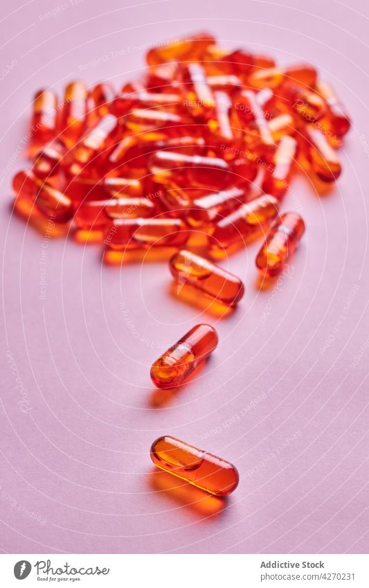 Orangefarbene Pillen auf rosa Oberfläche verstreut Tablette Medikament Kapsel Kur Streuung Zusammensetzung orange Abhilfe Vitamin Leckerbissen Apotheke