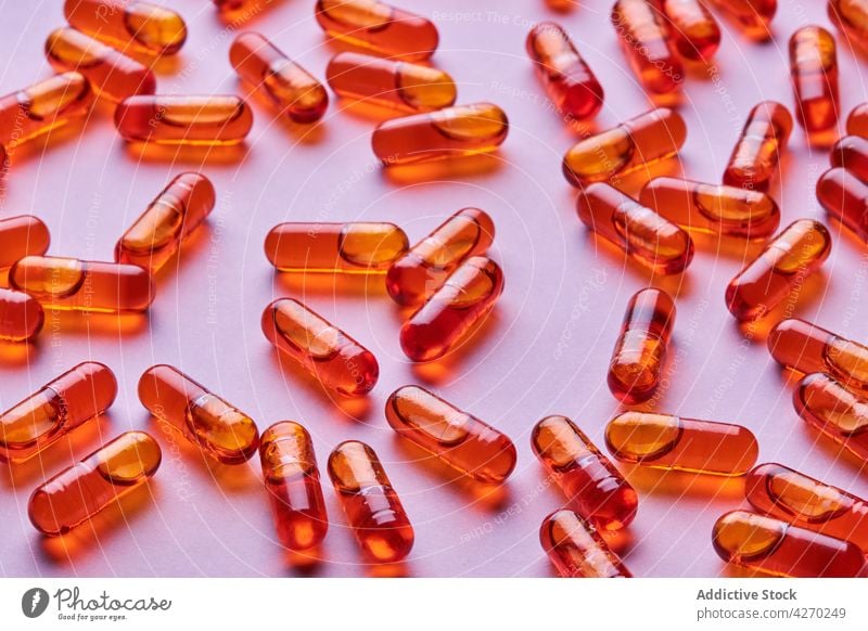 Orangefarbene Pillen auf rosa Oberfläche verstreut Tablette Medikament Kapsel Kur Streuung Zusammensetzung orange Abhilfe Vitamin Leckerbissen Apotheke