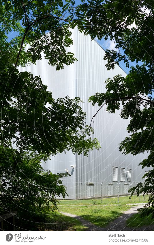 Aluminium Fabrikgebäude im Wald Bäume Silhouette Zaun Wiese Stacheldraht Stacheldrahtzaun Aluminiumfassade Überwachungskamera Gebäude Lagerhalle Wege & Pfade