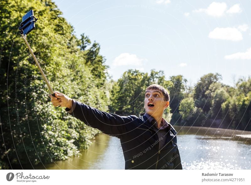 junger Mann macht Selfie mit einem Selfie-Stick männlich kleben Fotokamera Selbst Gesicht Porträt Glück Freizeit Hintergrund Person machen Smartphone Hand