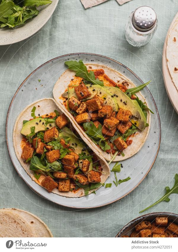 Leckere Tacos mit Tofu und frischen Avocadospalten Straßenessen Mittagessen Abendessen Rucola Sesam Tortilla lecker gebraten Samen Blatt Bohnenquark