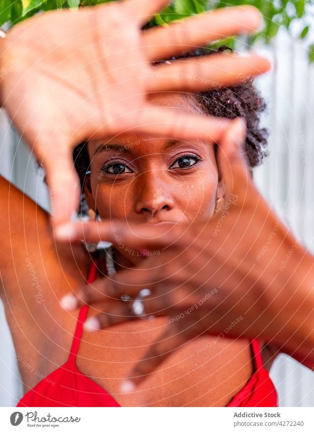 Schwarze Frau zeigt Rahmengesten bei Tageslicht Foto Perspektive feminin herzlich Starrer Blick sanft gestikulieren Porträt Stil freundlich rot Farbe Fotografie