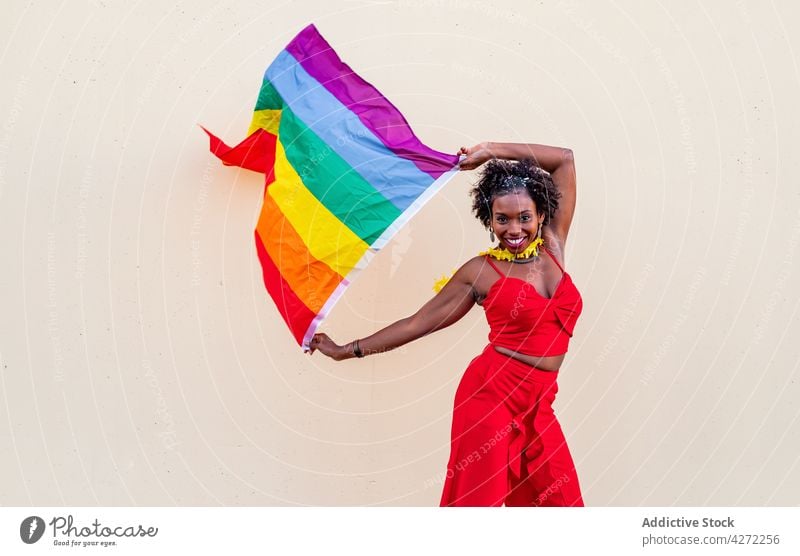 Stilvolle schwarze Frau mit LGBTQ-Flagge auf hellem Hintergrund lgbtq Fahne Mode Stolz Gleichstellung Toleranz Individualität Regenbogen Ornament feiern