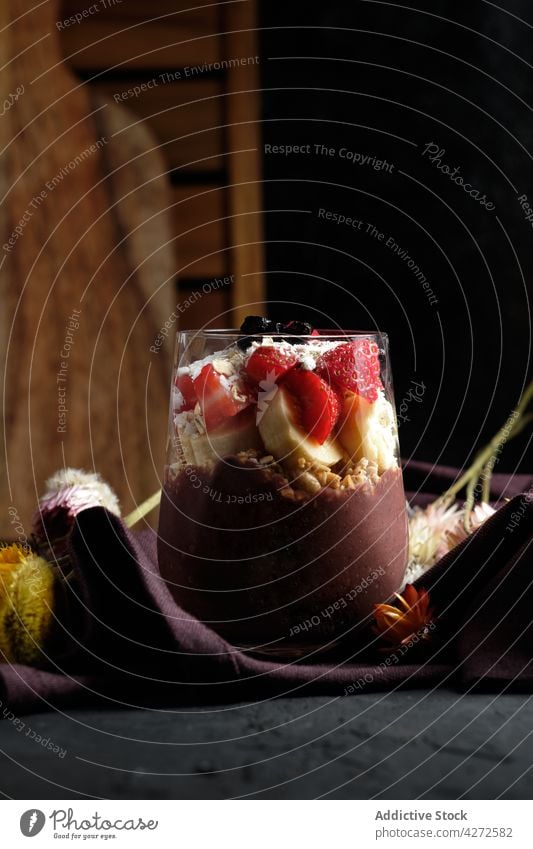 Leckeres Müsli mit Beeren, serviert auf dem Tisch neben frischen Blumen Smoothie Frühstück Erdbeeren Blaubeeren Ernährung Wildblume gesunde Ernährung lecker