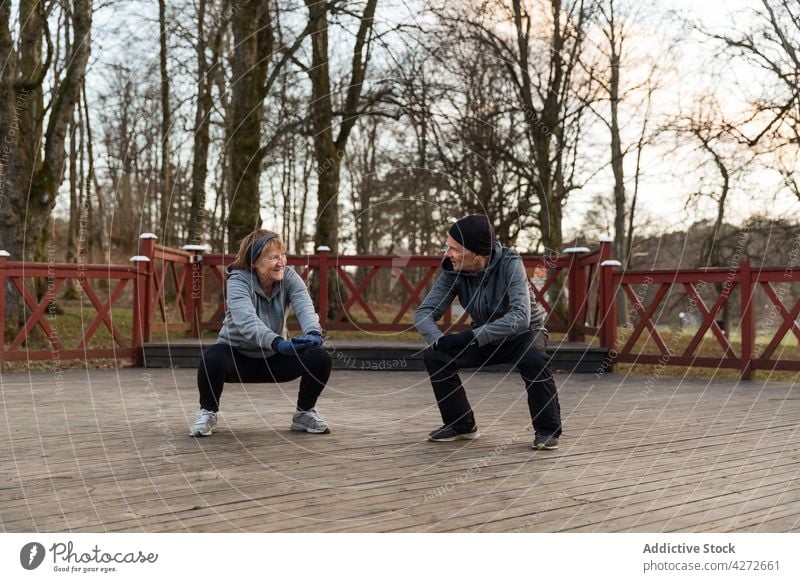 Positiv gealtertes Paar trainiert gemeinsam im Park Kniebeuge Übung anstrengen Aktivität Gesunder Lebensstil Training physisch Mann Frau aktiv Zusammensein