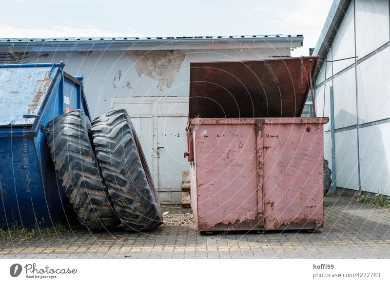 Stillleben zweier Altmetall Container mit großen Treckerreifen auf einem Werkstatthof treckerreifen Abfall Recyclingcontainer wiederverwerten Metall Entsorgung