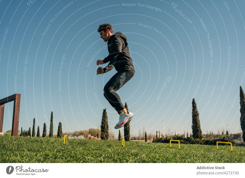 Aktiver Sportler springt beim Ausdauertraining im Park springen Herz Training Aktivität Übung Energie Mann dynamisch üben Turnschuh Sprung Wohlbefinden