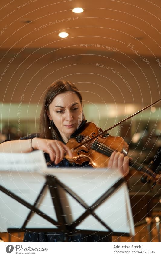 Eine Geigerin spielt klassische Musik in einem Saal Frau Musiker spielen ausführen Probe Instrument Fähigkeit Melodie Klang Talent Atelier akustisch Audio