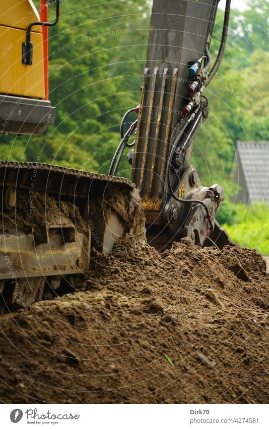 Detail eines Baggers auf einem Erdhaufen Baustelle Bauindustrie Schaufel Baggerschaufel Erde aushub ausheben baggern Kette Raupenkette Detailaufnahme Industrie