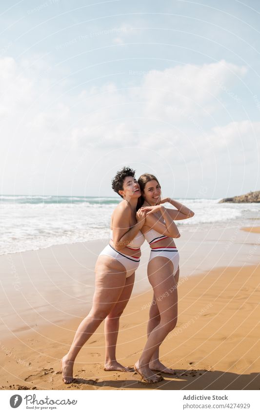 Damen im Meer stehend in der Nähe der sandigen Küste Frauen Freund Spaß haben Strand Lächeln Sand Badeanzug Blauer Himmel Glück aqua Meeresufer Sommerzeit jung