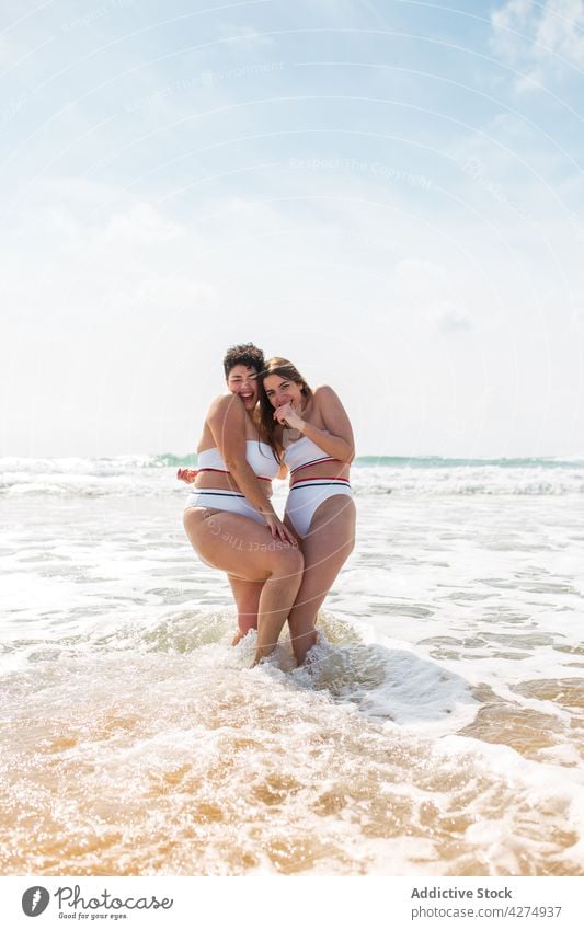 Damen im Meer stehend in der Nähe der sandigen Küste Frauen Freund Spaß haben Strand Lächeln Sand Badeanzug Blauer Himmel Glück aqua Meeresufer Sommerzeit jung