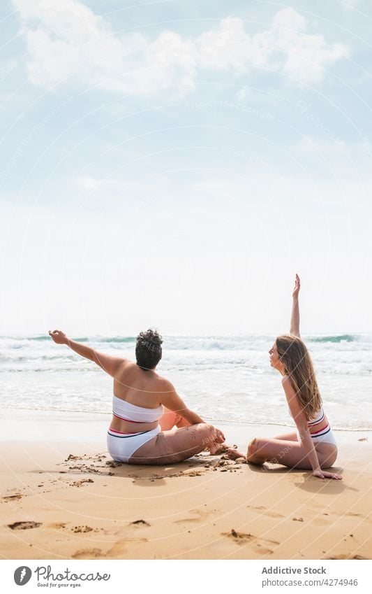 Anonyme Damen in Badekleidung am Sandstrand am Meer Frauen Strand Freund Badeanzug Urlaub Blauer Himmel jung bester Freund Zusammensein Ufer sitzen Freundin