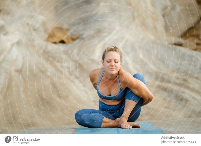 Frau zeigt Sage Marichis Pose gegen den Berg Yoga Dehnung Salbei Marichis Augen geschlossen Hand hinter dem Rücken nach vorne lehnen Konzentration Wellness