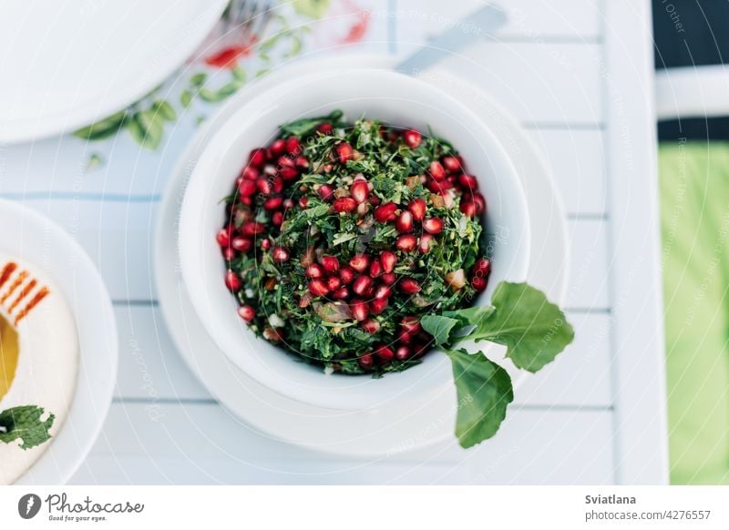 Auf dem Tisch in einem arabischen Restaurant steht ein Petersilien-Tabbouleh-Salat mit Granatapfelkernen. Blick von oben. Gesundheit grün Salatbeilage