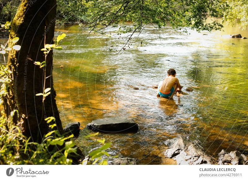 Junger Junge sitzt und spielt im Fluss Rückansicht kleiner Junge sitzend Sitzen jung Lifestyle männlich Person Kind Menschen niedlich Porträt Bildung Spielen