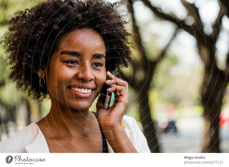 Geschäftsfrau beim Telefonieren im Freien. Afro-Look Business Frau Mobile reden modern Stil brünett Apparatur positiv Konzept Anschluss Anwendung SMS Texten