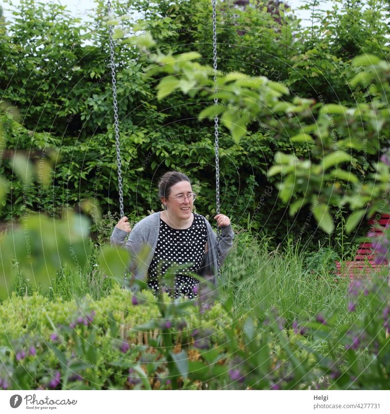 Glückliche Momente - auf einer Schaukel inmitten eines Blumengartens sitzt eine Frau und genießt den Augenblick Mensch schaukeln Garten Sträucher Natur