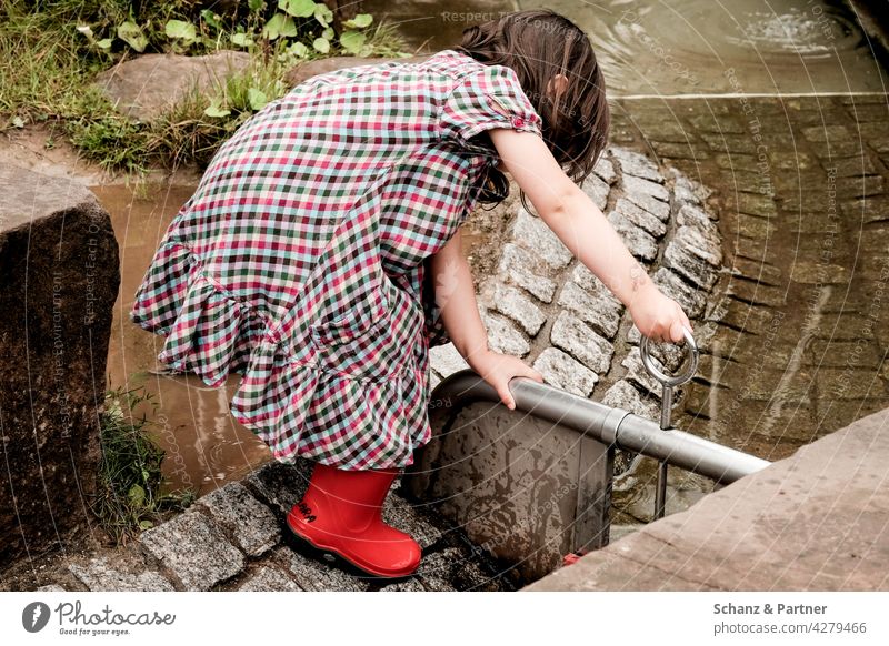 Mädchen spielt an einem Wasserspielplatz Kind spielen Gummistiefel Spielplatz Ausflug Familienausflug Kindheit Außenaufnahme Freude 3-8 Jahre Kindergarten