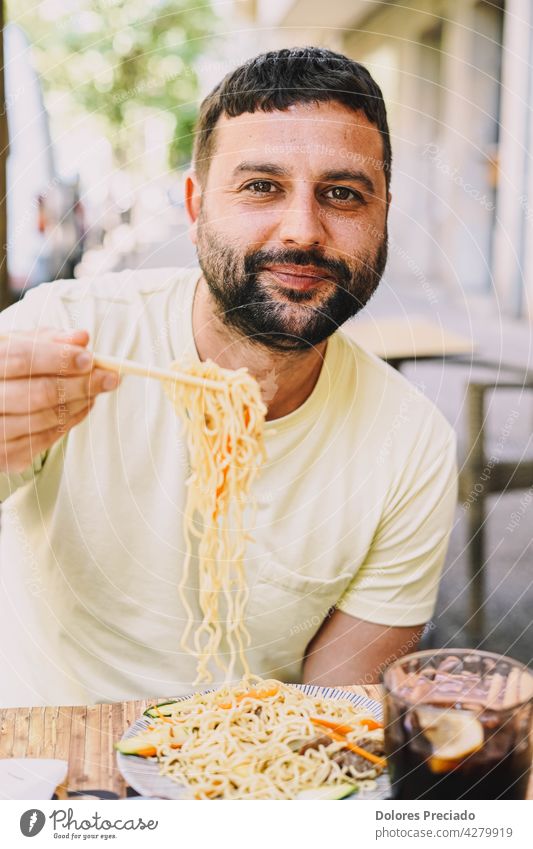 Latino Junge in gelben T-Shirt essen japanisches Essen Erwachsener Amuse-Gueule asiatisch attraktiv Avocado Hintergrund Kaukasier heiter Essstäbchen farbenfroh