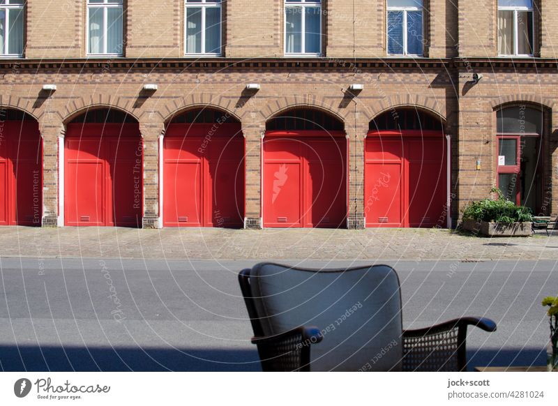 Sitzplatz vor dem Feuerwehrhaus Sessellehne Backsteinfassade Bogen Garagentor Ausfahrt Bürgersteig Symmetrie Architektur Einfahrt Prenzlauer Berg Berlin Stil