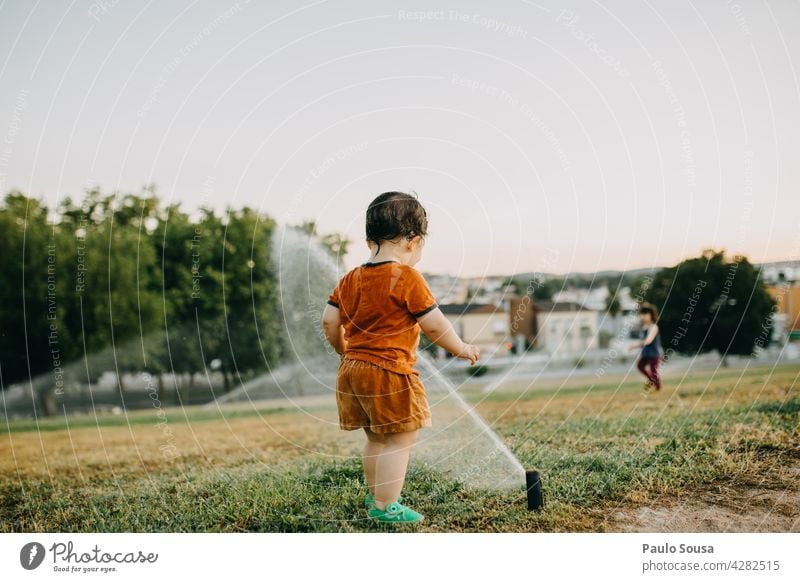 Bruder und Schwester spielen mit Wassersprinklern Kind Geschwister Sommer Sprinkleranlage Sprühen nass Bewässerung Freude Garten Ferien & Urlaub & Reisen gießen