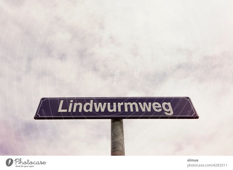 lila Straßennamensschild mit weißer Schrift " Lindwurmweg " vor bewölktem Himmel / Orientierung Straßenschild Straßennamenschild außergewöhnliche Straßennamen