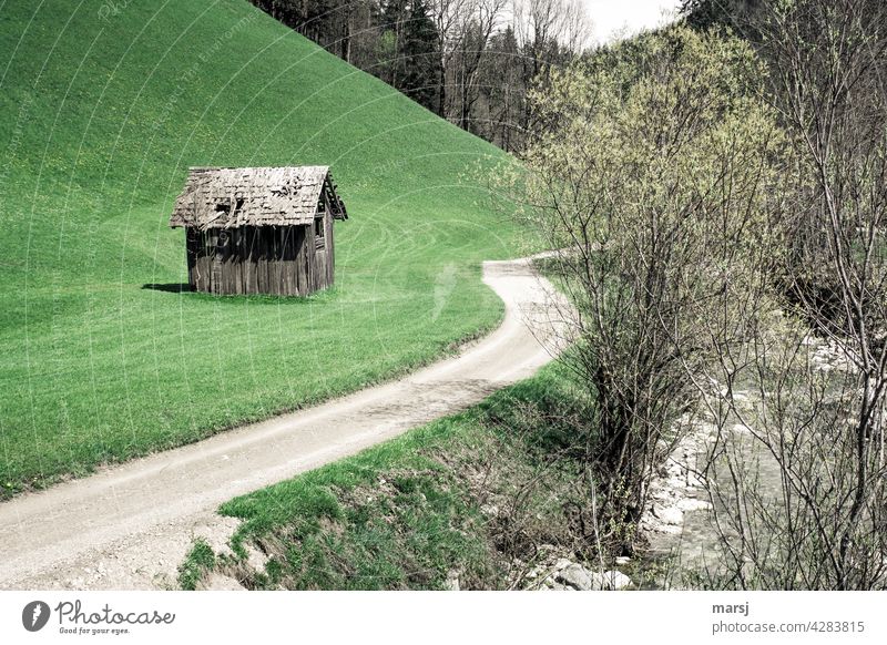 Häuschen im Grünen, mit eigener Zufahrt und Bach. Einsamer Heustadl auf einer Wiese neben einem Feldweg. Hütte Farbfoto alt Kontrast Natur Heuschober Haus