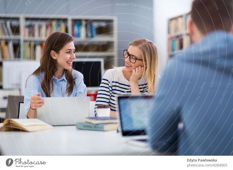 Junge Studenten in einer Universitätsbibliothek genießend Lifestyle jung Erwachsener Menschen lässig Kaukasier positiv Glück Lächeln Frau attraktiv schön