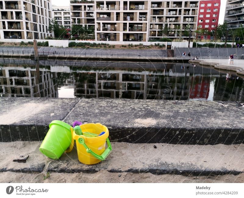 Bunte Plastikeimer mit Schaufel und Förmchen an einem Sandkasten des Kinderspielplatz am Mainkai am Hafenplatz mit moderner Architektur im Sommer in Offenbach am Main in Hessen