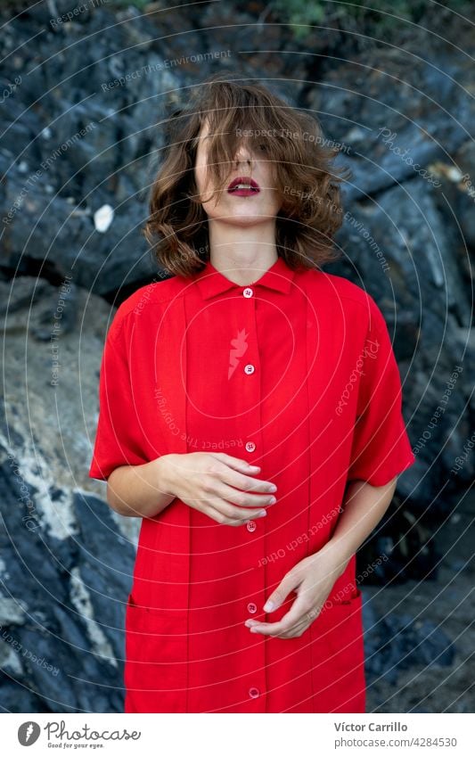 Eine elegante modische frische schöne Frau in einem roten Vintage-Kleid mit Felsen Hintergrund. Porträt Schönheit jung Mode Model Behaarung Gesicht Person