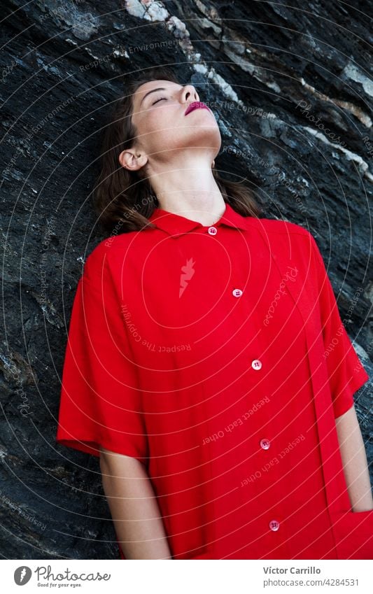 Eine elegante modische frische schöne Frau in einem roten Vintage-Kleid mit Felsen Hintergrund. Porträt Schönheit jung Mode Model Behaarung Gesicht Person