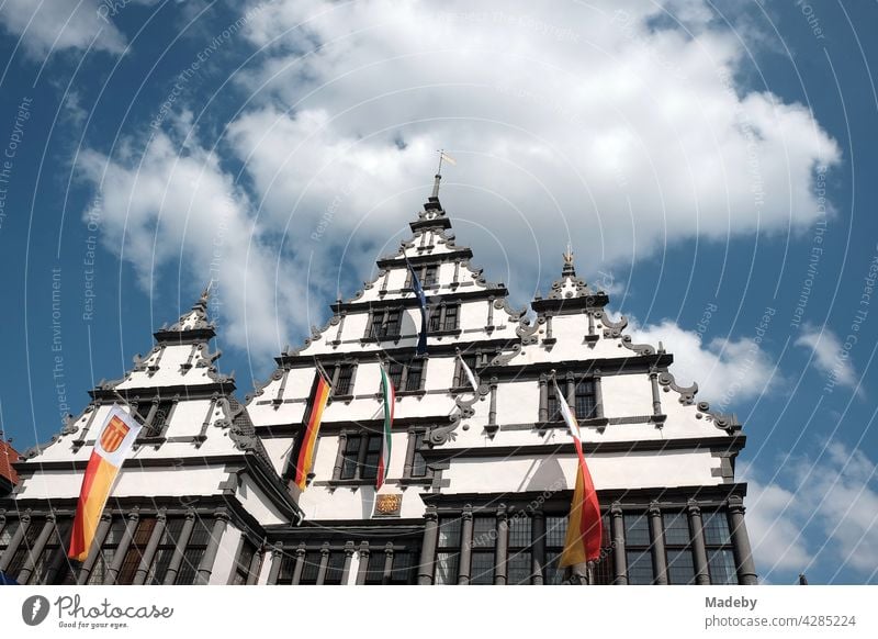 Das historische Rathaus im Stil der Weserrenaissance mit Fahnenschmuck bei Sonnenschein in der Bischofsstadt Paderborn in Ostwestfalen-Lippe Altbau Wahrzeichen