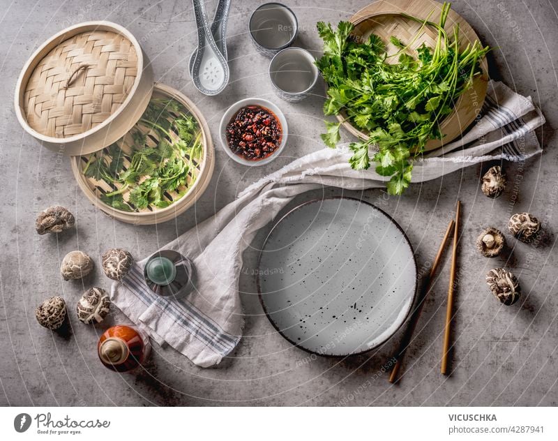 Vegane Knödel serviert mit Saucen und frischen asiatischen Kräutern auf dem Teller und im Dämpfer. Traditionelles Speisenkonzept mit hochwertigen Zutaten und feinen Shiitake-Pilzen . Ansicht von oben