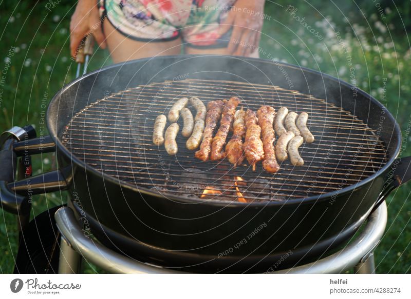 Grillen mit Bratwürsten und Fleischspieße mit Rauch über der heißen Glut Bratwurst Grillrost Grillsaison Steak Barbecue gegrillt Grillkohle Essen Ernährung